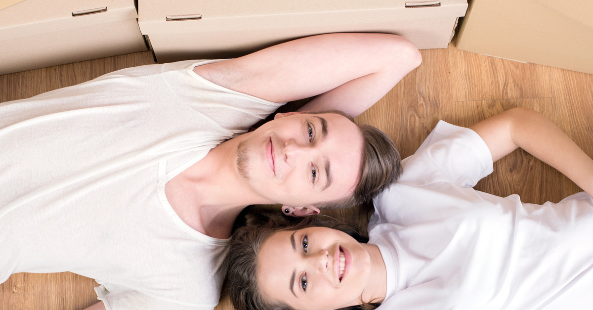 Young couple in white shirts lying on the ground with moving boxes