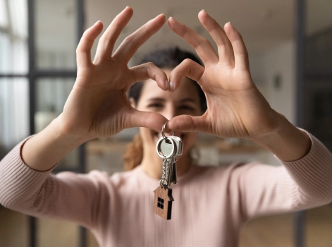 Woman forming a heart shape with her hands around a house key.