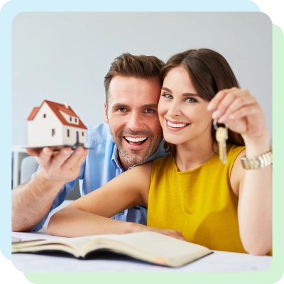 a couple holding miniature model house and a set of house keys