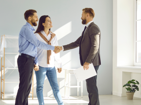 Couple shakes hands with a real estate agent in a modern room as they buy their million dollar home