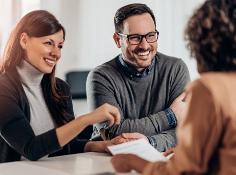 Happy couple discussing paperwork with a professional, showcasing a seamless and supportive mortgage process for their homeownership journey.